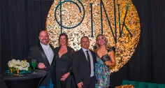 Three guests beside a tree-themed backdrop at Paint the Town PINK