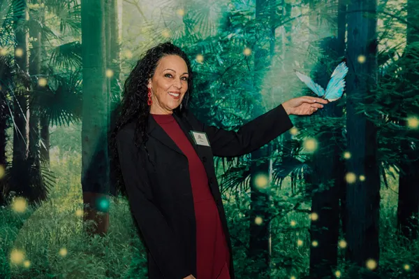 Guest beside a forest-themed photo backdrop at Paint the Town PINK