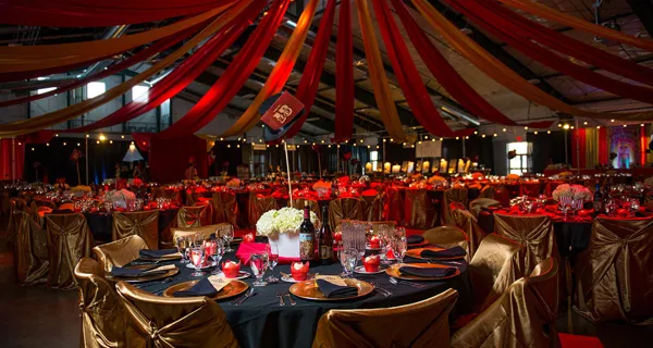 Banquet tables under red and yellow drapes at Paint the Town PINK